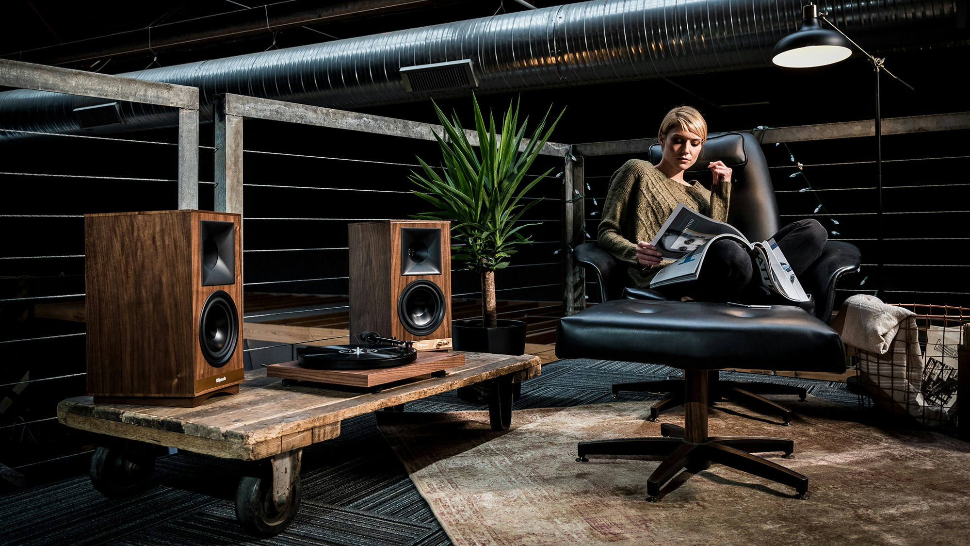 Lady reading a magazine and listening to Klipsch The Sixes powered speakers